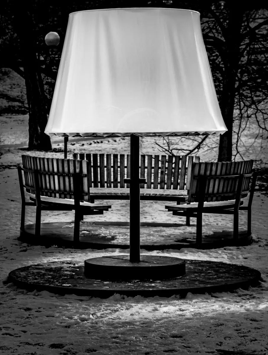 Oversized floor lamp standing outdoors among benches